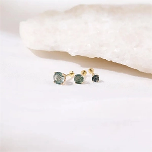 Detailed view of three graduated round moss agate studs with gold claw settings