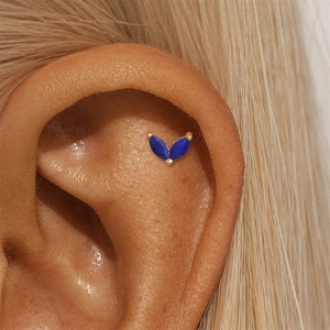 Macro shot of gold ear piercing stud with two blue marquise-cut stones in a V-shape design