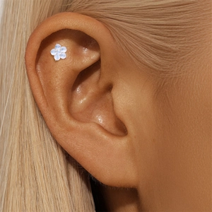 Detailed close-up of a five-petal moonstone flower tragus earring on a female ear