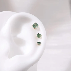 Detailed macro view of three Moss Agate stud earrings in graduated sizes on a silicone ear model