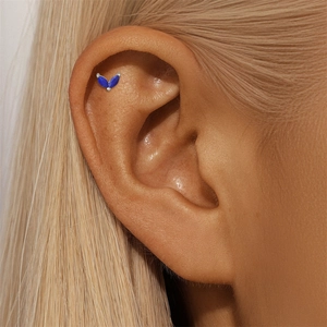 Macro view of blue marquise-cut lapis lazuli clover stud earring on human ear