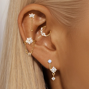 Detailed view of s925 silver gold ear piercings set with opal stars and moon charms