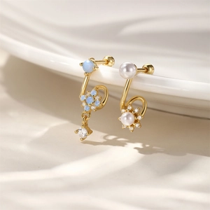 Macro view of gold S925 silver stud earrings with blue opal, pearl and sparkling crystals