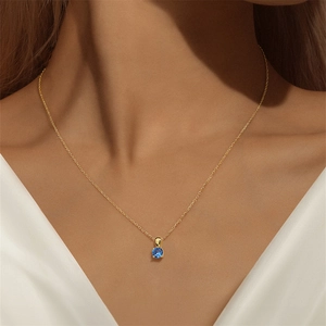 Close-up van S925 zilveren gouden ketting met een blauwe saffier hanger op de nek