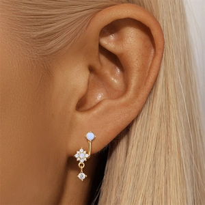 Close-up of gold flower cartilage earring with blue opal stone and zircon drop