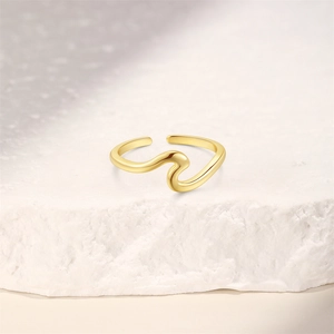 Macro shot of minimalist gold wave toe ring on white natural stone with high-shine finish