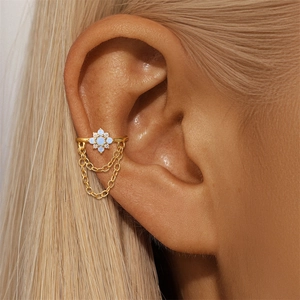 Dettaglio del ear cuff a fiore in argento s925 dorato con opale blu e nappe sull'orecchio