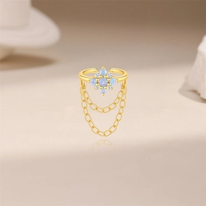 Dettaglio ear cuff dorato a fiocco di neve con opale blu e catenine pendenti nappe