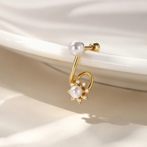 Detailed macro shot of a gold U-shaped earring with white pearls and small diamonds