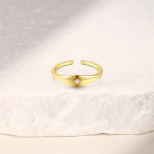 Close-up of a gold star-shaped adjustable ring with a zircon stone on a white stone background
