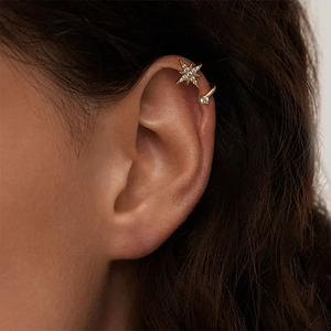Dettaglio di un ear cuff a stella dorata con zirconi brillanti indossato da una modella