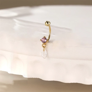Macro detail of a gold belly ring with purple round gemstone and marquise crystal drop