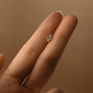 Macro detail of gold S925 green moss agate stud earring held between fingers