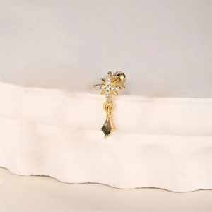 Detailed view of a gold star stud earring with a dark green teardrop gemstone pendant