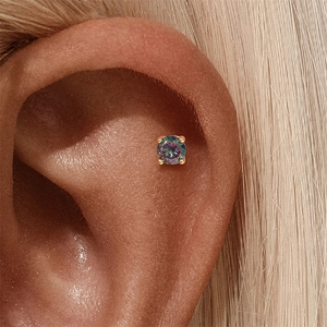 Detail van s925 zilveren oorbel met mystic topaz en gouden vier-klauws zetting op het oor
