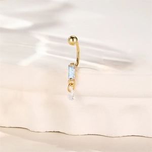 Macro view of gold navel ring with blue rectangular stone and teardrop crystal drop