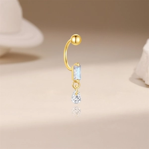 Detail view of a gold belly button ring with blue gem and drop-shaped zircon pendant