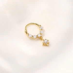 Detailweergave van gouden piercing ring met zirkonia inleg en vijfpuntige ster hanger