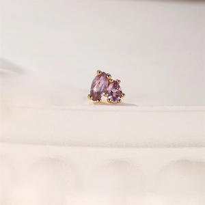 Macro shot of purple gemstone ear stud with gold claw setting on stone base