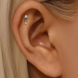 Macro shot of s925 gold helix piercing with green moss agate and sparkling zircon