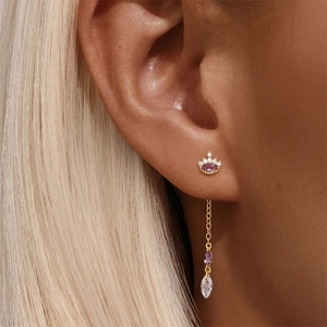 Macro detail of gold crown earring with purple marquise stone and long chain tassel