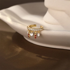 Dettaglio del ear cuff dorato con fiori in zirconia e pendenti a goccia rossi