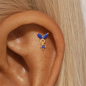 Detail of s925 gold ear stud with lapis lazuli gemstones worn on female ear cartilage
