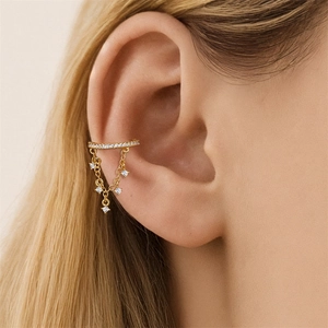 Vista macro dell'ear cuff dorato con zirconi brillanti e delicate catene a frange