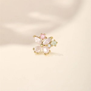 Macro view of gold flower cartilage stud with pink and green stones in claw setting