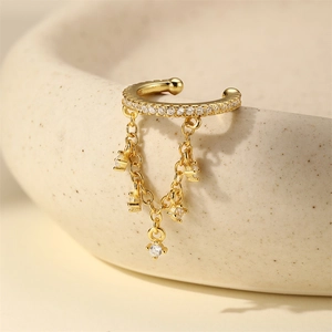 Dettaglio di ear cuff dorato con pietre marquise e nappe di zirconi su ceramica