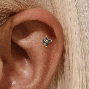 Detailopname van gouden bloemknopoorbel met aurora-edelstenen op een model