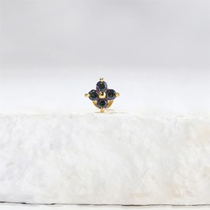 Detail van gouden bloem piercing met paars en groen iriserende edelstenen