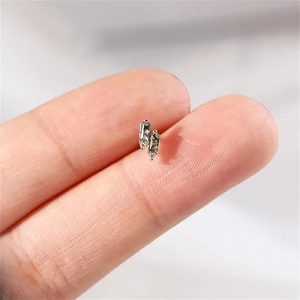 Macro shot of tiny gold moss agate stud earrings with rectangle stones on a fingertip