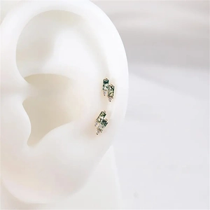 Close-up of rectangular moss agate stud earrings with diamond accents on a model ear