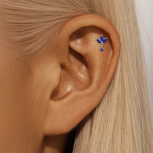 Macro shot of silver s925 four-leaf clover ear stud with blue lapis lazuli on ear