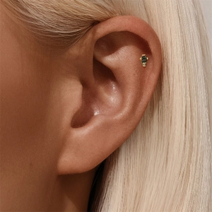 Macro detail of gold snake stud with coffin-cut green moss agate on ear cartilage