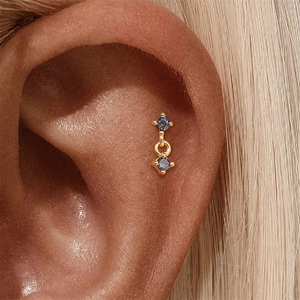 Close-up van s925 zilveren regenboogsteen oorbellen met blauwe en paarse glans op oor