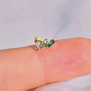 Macro shot of minimalist gold s925 earring with green moss agate on a fingertip