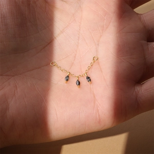 Nahaufnahme einer goldenen Kette mit drei schwarzen Markasit-Anhängern auf der Hand