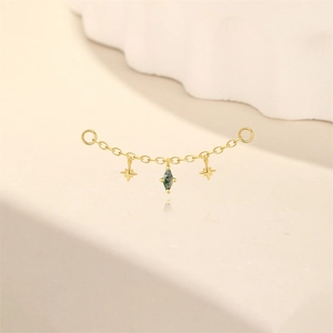 Nahaufnahme einer Goldkette mit grünem Marquise-Edelstein und zierlichen Stern-Anhängern
