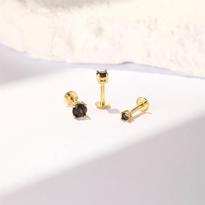 Macro view of gold S925 sterling silver stamp and black gemstone on labret studs