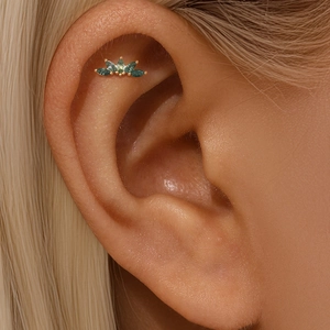 Close-up of green moss agate stones in gold fan setting worn on the ear cartilage