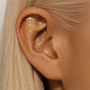 Macro shot of gold-plated S925 silver cartilage stud with zircon leaf and chain tassels