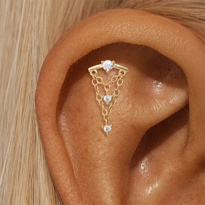 Macro shot of 16G gold cartilage stud with three zircons and layered tassel chains