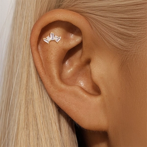 Macro shot of 925 sterling silver ear stud with baguette cut zircons on ear cartilage
