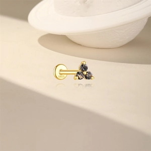 Macro detail of S925 sterling silver stamp on golden piercing stud with black stones