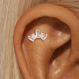 Macro shot of s925 silver crown-shaped stud with zircon on the ear cartilage