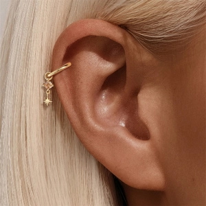Dettaglio di ear cuff dorato con gemma color champagne e piccolo pendente a stella