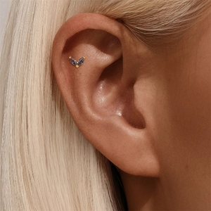 Gedetailleerde macro-opname van een vergulde V-piercing met iriserende marquise geslepen stenen