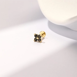 Macro view of gold clover earring with black gemstone and flat back piercing